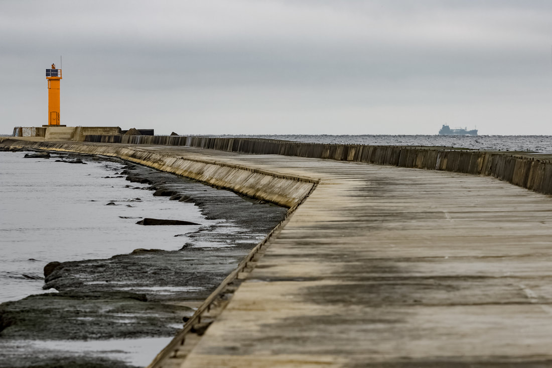 Picture of seawall along a pier leading out to a lighthouse in Lake Michigan.